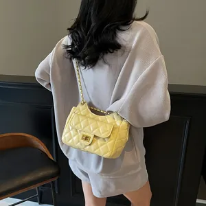 Sac à bandoulière matelassé jaune avec chaîne dorée porté par un mannequin en tricot