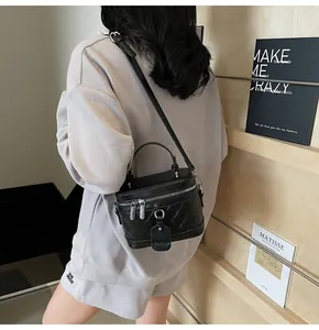 Detail of black quilted bucket bag with silver hardware and adjustable leather strap