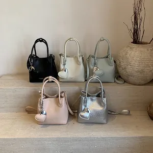 Mini leather bucket bag with heart charm in black, white, blue, pink, and silver