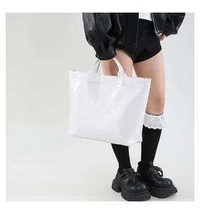 Detailed view of white crocodile embossed tote bag with 3D embossed text on glossy faux leather