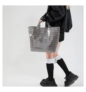 Close-up of silver wave-textured faux leather tote bag with white TOTE BAG lettering