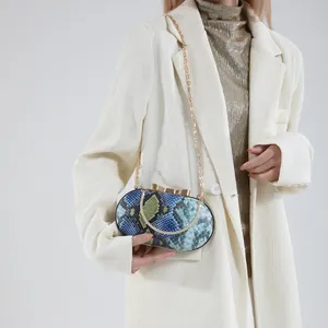 Sac à main en serpent bleu sarcelle avec fermoir nœud doré et bandoulière chaîne