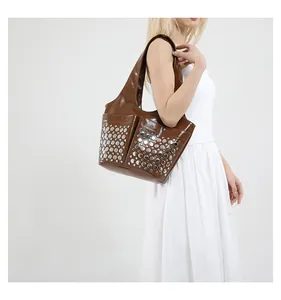 Brown glossy tote bag with silver studs and external pockets shown on shoulder