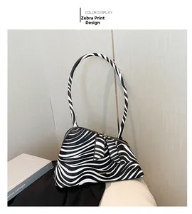 Détail du sac à bandoulière zébré avec fermeture éclair dorée et logo métallique