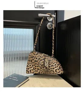 Détail d'un sac léopard avec double fermeture éclair dorée et pompon élégant