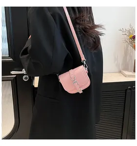 Detail der rosa Satteltasche mit Litschi-Struktur und Schnalle an einem schwarzen Blazer