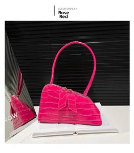 Détail d'un sac à main rouge rose à motif crocodile avec arc asymétrique et logo métal