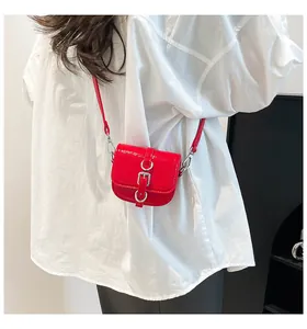 Nahaufnahme der roten Mini-Satteltasche aus glänzendem Lackleder mit Silberbeschlägen