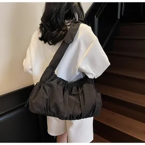 Detail of black ruched cloud bag with wide shoulder strap worn by a model in casual style