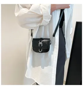 Minitasche aus schwarzem Lackleder mit Metallschnalle getragen von einem Modell