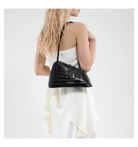Détail d'un sac à bandoulière noir brillant à motif crocodile avec texte élégant