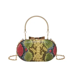 Python snakeskin pattern evening clutch bag with gold handle and bow clasp on white background