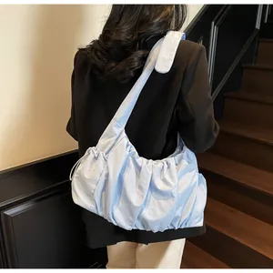 Detail of light blue ruched cloud bag with textured fabric on model's shoulder
