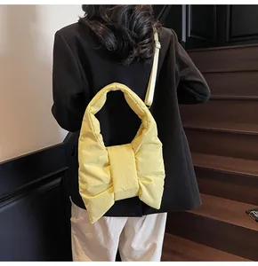 Detailed view of a bright yellow padded bow shoulder bag worn over a black blazer