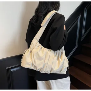 Detail view of beige ruched shoulder bag with drawstring accents and pleated nylon texture