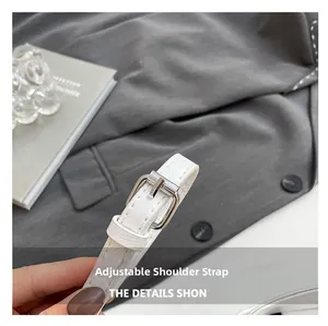 Detail of adjustable white leather strap with silver buckle on a textured handbag