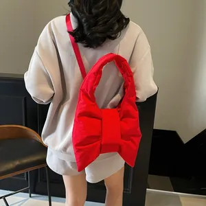 Chic oversized red bow shoulder bag with padded nylon fabric and minimalist aesthetic
