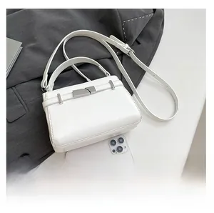 Detailed view of white lychee grain leather handbag with silver lock and smartphone for scale