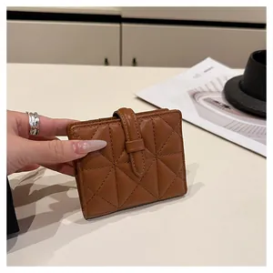 Dettaglio porta carte in pelle trapuntata marrone con cinturino nella mano