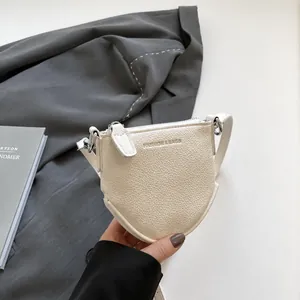 Détail du petit sac bandoulière en cuir grainé crème avec structure en forme de bouclier