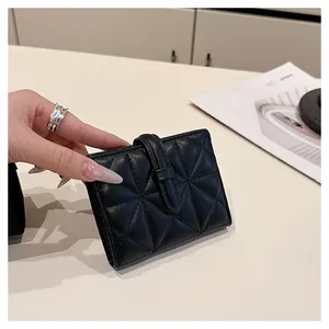Dettaglio del portacarte in pelle trapuntata nera con cinturino e design compatto elegante