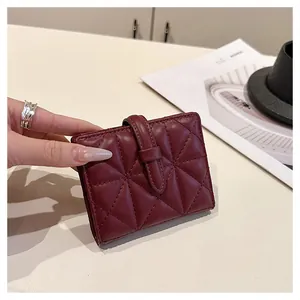 Dettaglio del portafoglio trapuntato in pelle bordeaux con chiusura a cinturino