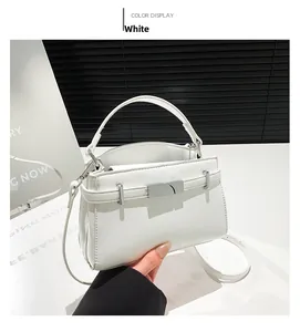 Close-up of a white leather handbag featuring a silver metal clasp and a top handle