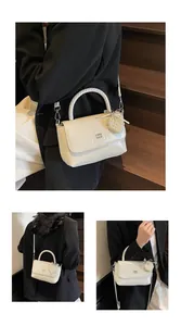 Detail view of cream white handbag featuring woven handle and elegant pearl heart charm