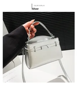 Close-up of a silver metallic kelly bag with top handle and rectangular metal buckle