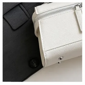 Detailansicht der weißen Tasche mit Litschi-Muster, Reißverschluss und Metallfüßen