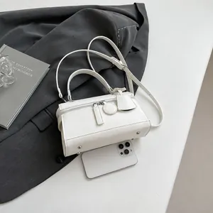 Handtasche aus weißem Lychee-Leder im Größenvergleich mit Smartphone und Anzug