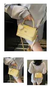 Detail of yellow leather handbag with woven handle, pearl heart charm and crossbody strap