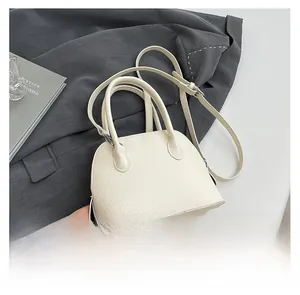 Détail du sac bandoulière crème en cuir grainé posé sur une veste de blazer grise