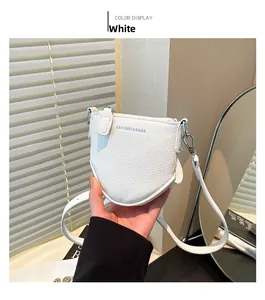 Détail d'un mini sac bandoulière blanc en cuir grainé avec logo fashion bleu chic