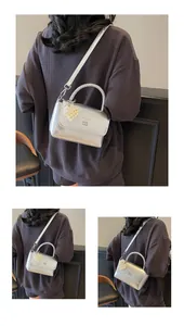 Detail of silver crossbody bag with woven handle and pearl heart charm accessory
