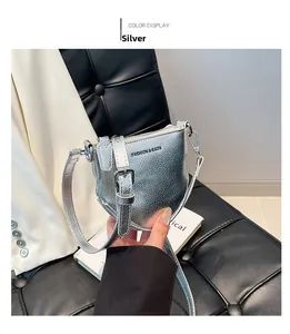 Détail d'un petit sac bandoulière argenté avec texture grainée et fermeture éclair en métal