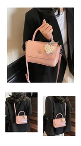 Detail of pink leather handbag with woven handle, pearl heart charm and shoulder strap