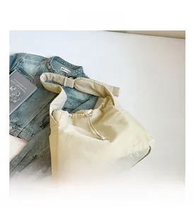 Detail of beige tote bag featuring drawstring closure and functional side pocket detail