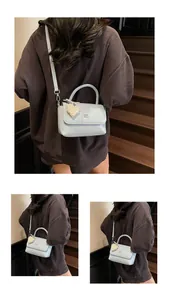 Close-up of light blue textured handbag with braided handle and pearl heart charm