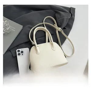 Gros plan d'un sac coquille blanc en cuir grainé avec poignées et bandoulière