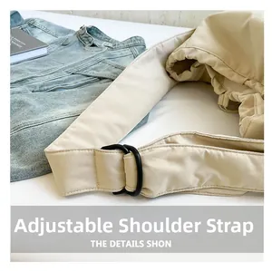 Detail of adjustable wide canvas shoulder strap with matte black metal rings on a beige tote