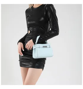 Light blue faux leather handbag with silver hardware held by a model in a black dress