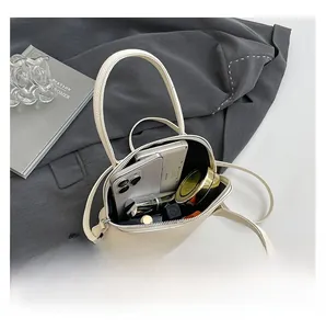 Vue intérieure du sac en cuir crème montrant smartphone, rouge à lèvres et maquillage