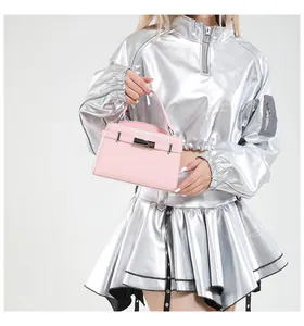 Pink top handle bag with metal bar lock and smooth leather texture on a silver outfit