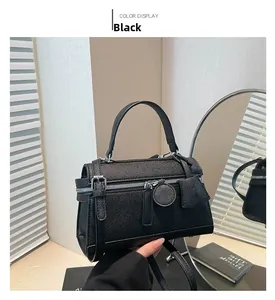 Detail einer schwarzen Lederhandtasche mit Metallschnalle und kreisförmigem Anhänger