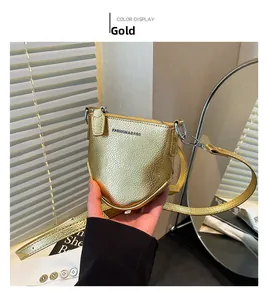 Détail du mini sac carré doré montrant la texture litchi et le lettrage à la mode