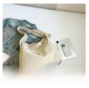 Detail of soft off-white nylon tote bag with drawstring closure and wide adjustable strap