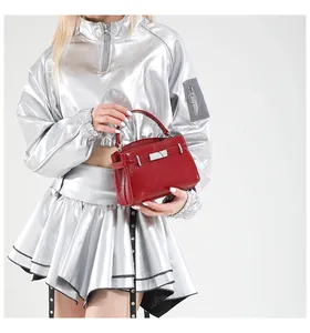 Detail of red high-gloss textured handbag with silver buckle worn by a model