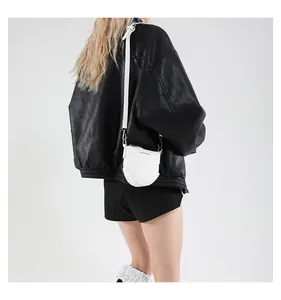 Sac bandoulière demi-lune blanc avec sangle réglable porté sur une veste en cuir noir