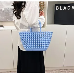 Light blue hollow woven tote bag shown as a stylish handheld accessory on a model